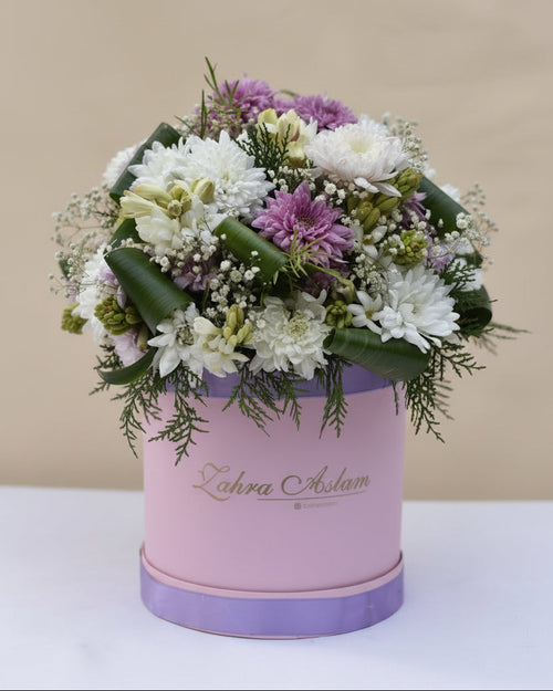 Floral arrangement in a pink and purple container on a light blue background